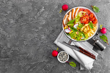 Grilled chicken meat with fresh vegetable salad of tomato, cucumber, radish, lettuce, mangold leaves, corn and pasta for lunch, top view