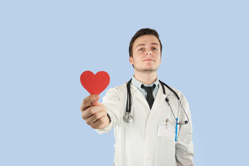 european doctor in a dressing gown with a red heart in his hands on an isolated blue background.The concept of health, gifts and holidays