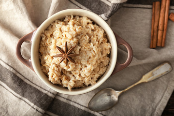 Pot with tasty oatmeal on table