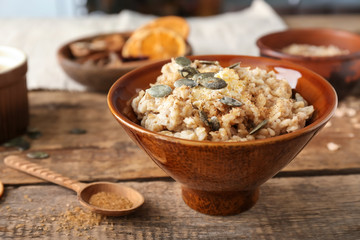 Bowl with tasty oatmeal on wooden table