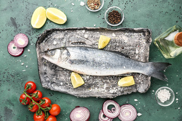 Plate with tasty fresh seabass fish on color background