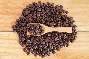 coffee beans and ground coffee in spoon on textured wood, close up, top-view.