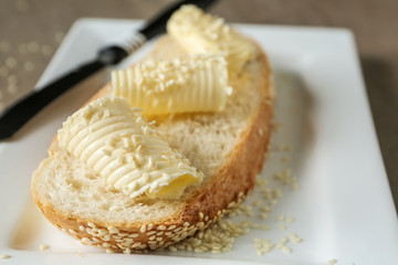 Piece of bread with butter curls on plate, closeup