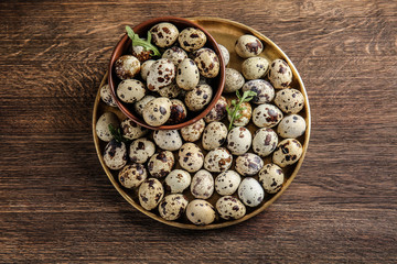 Plate and bowl with fresh quail eggs on wooden table