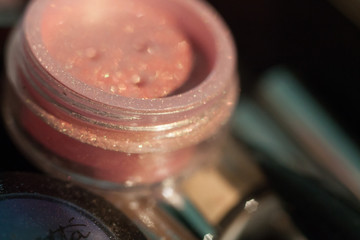 Cosmetics. Makeup. Jar with shadows, crumbly glitter, rouge. Closeup