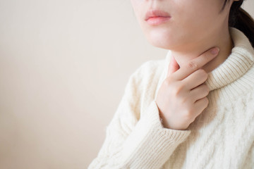 Sick women suffering from sore throat during winter season. Causes of throat pain include flu,...