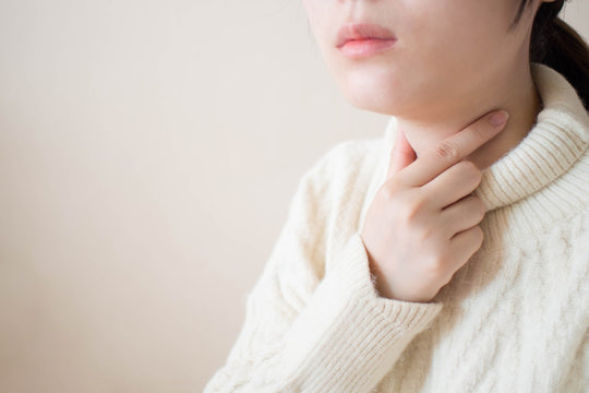 Sick women suffering from sore throat during winter season. Causes of throat pain include flu, common cold, respiratory tract infections or allergies. Close up. Copy space. Health/medical concept.