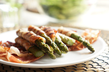 Plate with tasty bacon wrapped asparagus on table, closeup
