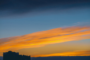Cityscape with wonderful varicolored vivid dawn. Amazing dramatic blue cloud sky above dark...