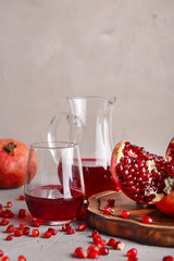 Ripe pomegranates and glassware with juice on table
