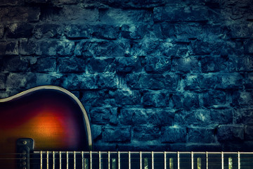 Old vintage jazz guitar on a brick wall background. Copy space. Background for concerts, festivals,...