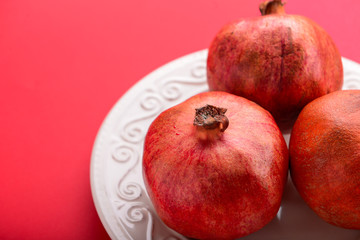 Plate with ripe pomegranates on color background, closeup