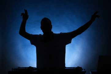 Silhouette of male DJ playing music on color background