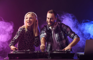 Fototapeta na wymiar Male and female DJs playing music in club