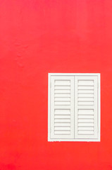 Simple duotone white closed window and bright red wall of building exterior flat facade with space for text