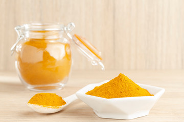 turmeric powder in glass bowl on wood