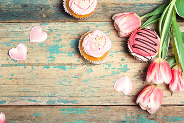 Tasty cupcakes with tulips on vintage wooden table with copy space. Romantic love background.
