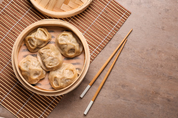 Bamboo steamer with tasty dumplings on grey table