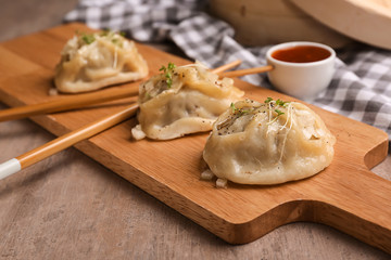 Fototapeta na wymiar Wooden board with tasty dumplings on table