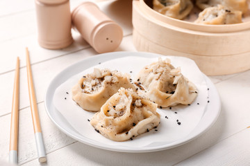 Plate with tasty dumplings on white table