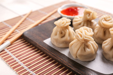 Wooden board with tasty dumplings on table