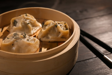 Bamboo steamer with tasty hot dumplings on table