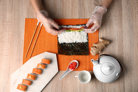 Woman Making Tasty Sushi Rolls At Table