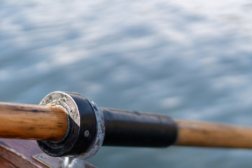 Closeup photo of wooden paddle attached to boat used for rowing in the water, lake Bled on a sunny day