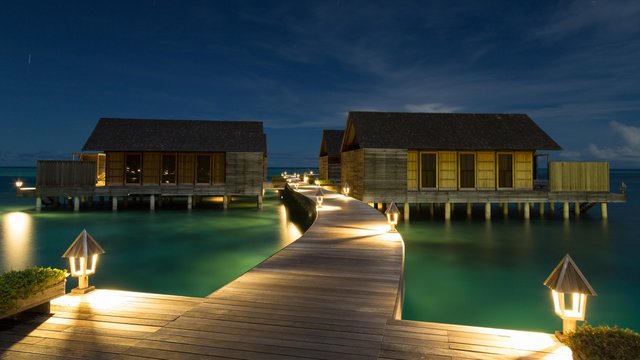 Wooden huts on stilts in lagoon at night, Gangehi Island, Ari Atoll, Indian Ocean, Maldives, Asia
