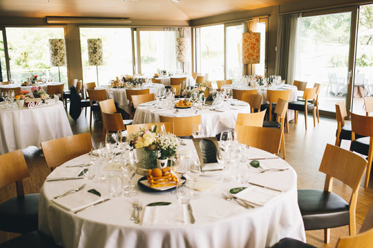 Wedding Dinner Table Setting. Brown Chairs Stand At The Round Tables Ready For Festive Dinner