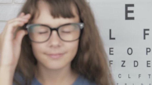 Child at the ophthalmologist. Cute little girl with poor eyesight wearing glasses.