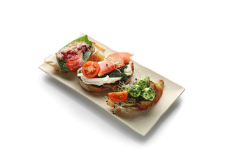 Plate with fresh tasty bruschettas on white background