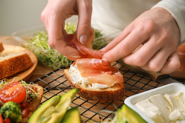 Woman preparing tasty bruschettas in kitchen, closeup