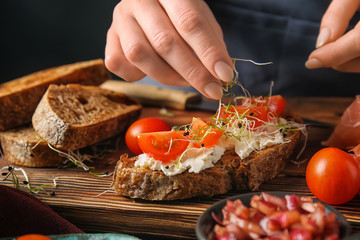 Woman preparing tasty bruschettas in kitchen, closeup