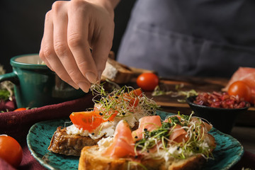 Woman preparing tasty bruschettas in kitchen, closeup