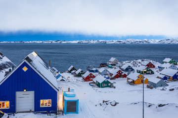 Colorful inuit huts among rocks and snow at the fjord in a suburb of arctic capital Nuuk, Greenland © vadim.nefedov