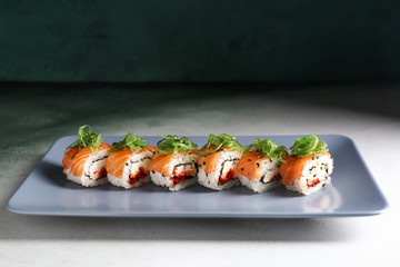 Plate with tasty sushi rolls on table