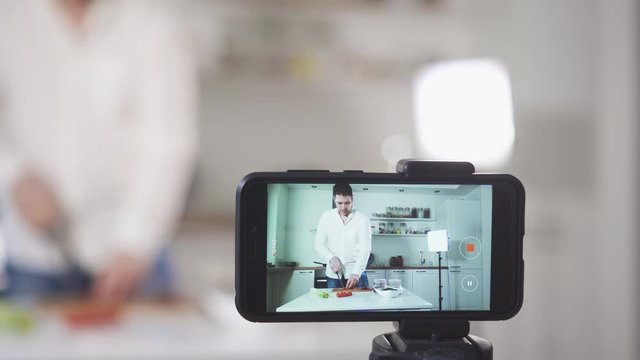 Man on the kitchen filming video. Vlogging concept.