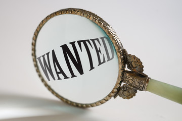 vintage magnifying glass enlarged text Wanted, search concept