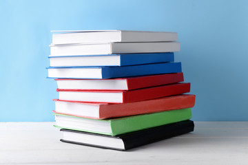 Many books on table against color background