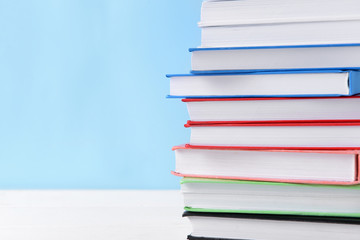 Many books on table against color background