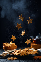 Falling stars shaped cookies with powdered sugar. Vertical composition on a dark background	