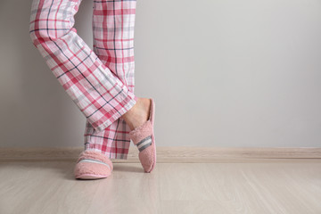 Young woman in slippers near white wall