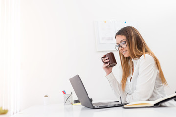 Obraz na płótnie Canvas Gorgeous designer girl with eyeglasses enjoying in a coffee break in the office.