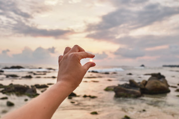 Girl holding the sun in her hand. Girl pulls her hand to the sea.