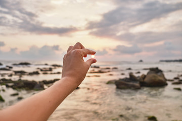 Girl holding the sun in her hand. Girl pulls her hand to the sea.