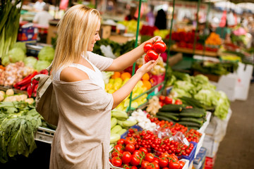 Cute young woman buying vegetables at the market