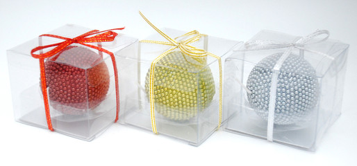 Red, golden yellow and silver grey candles in the transparent plastic box with ribbon