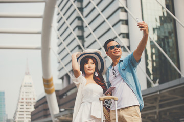 Couple travel to bangkok and selfie happily.Travel tourist couple traveling in thailand.Young asian couple with travel bag holding hands, walking in city.Honeymoon trip, backpacker tourist.