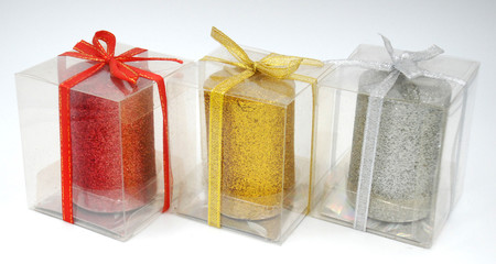 Red, golden yellow and silver grey candles in the transparent plastic box with ribbon